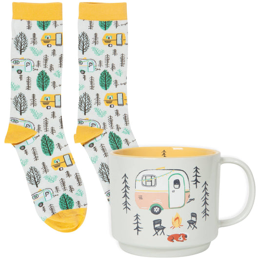 A set of gift items featuring a white stoneware mug with camping-themed patterns and socks with a similar design.