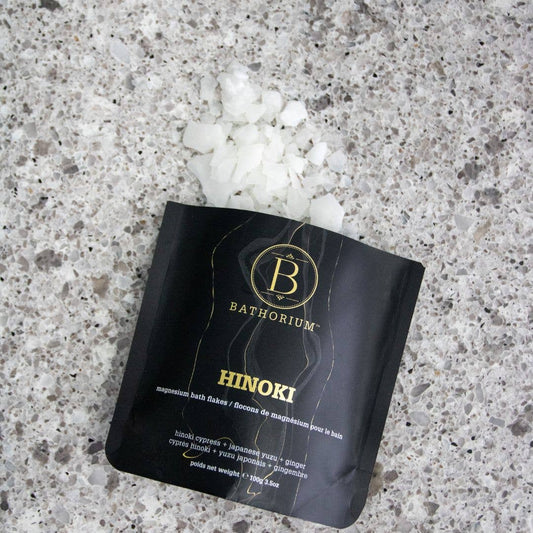 Bathorium Hinoki magnesium bath fakes packaging on a textured surface with white crystals.