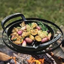 A black cast iron skillet with ergonomic handles in a backyard bbq.